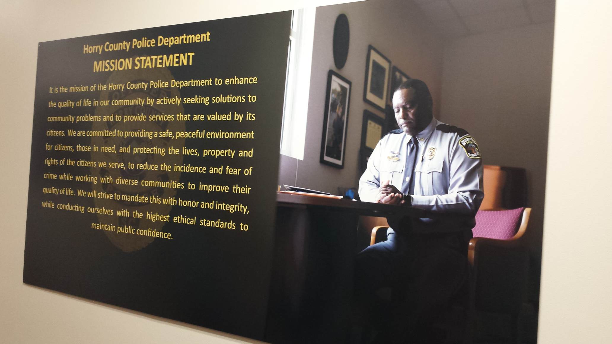 Officer reading near police department mission statement.